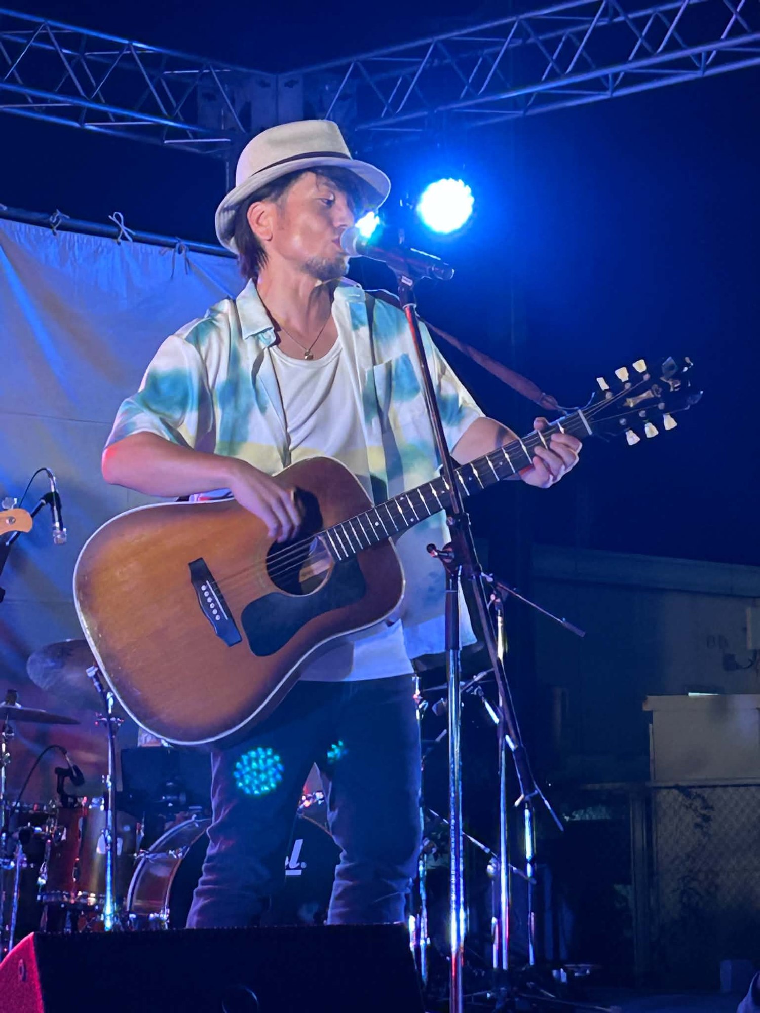 青い照明の中でアコースティックギターを演奏する池端克章